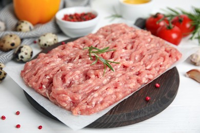 Photo of Raw chicken minced meat with rosemary and spices on white wooden table, closeup