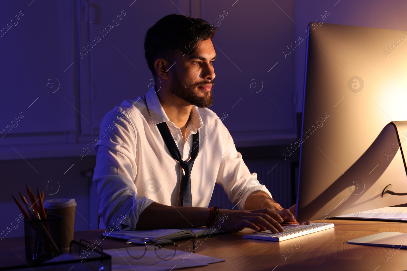 Photo of Tired young man working late in office