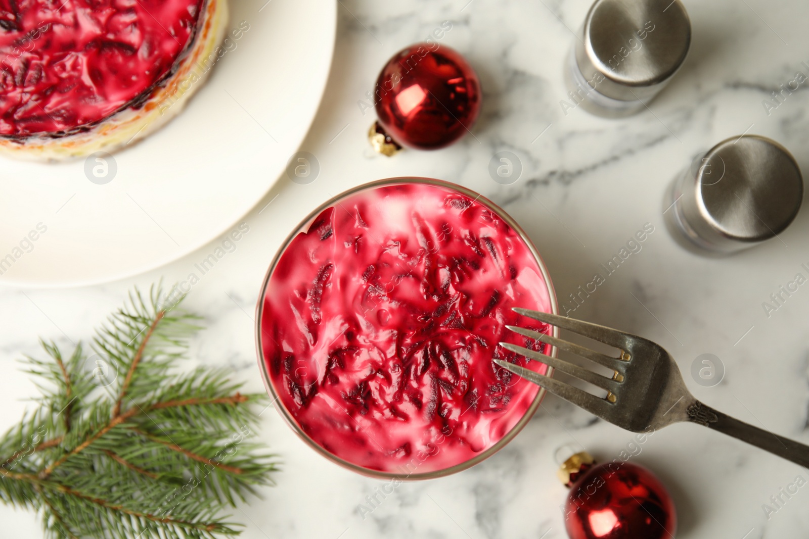 Photo of Flat lay composition with herring under fur coat, baubles and fir branch on white marble table. Traditional russian salad