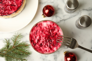 Photo of Flat lay composition with herring under fur coat, baubles and fir branch on white marble table. Traditional russian salad