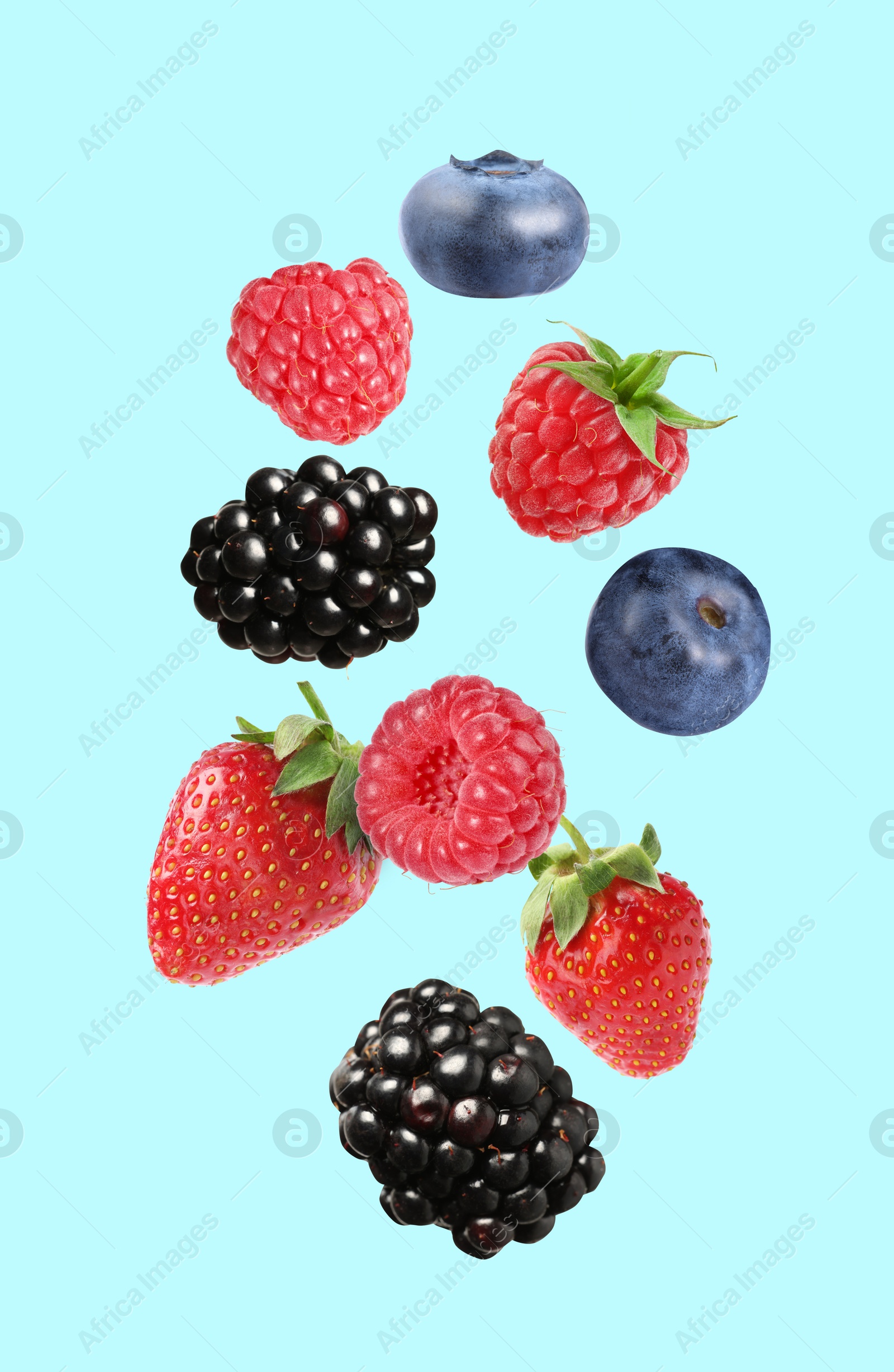 Image of Blackberries, blueberries, strawberries and raspberries falling on light blue background