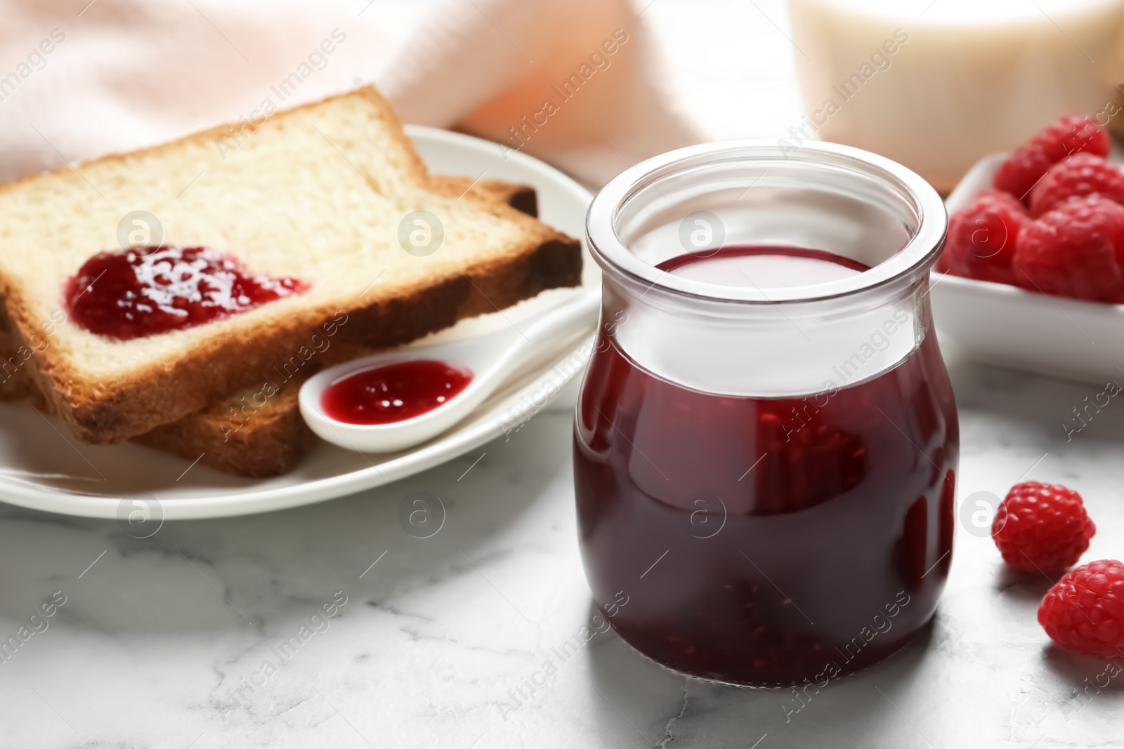 Image of Sweet raspberry jam and toasts for breakfast on white marble table