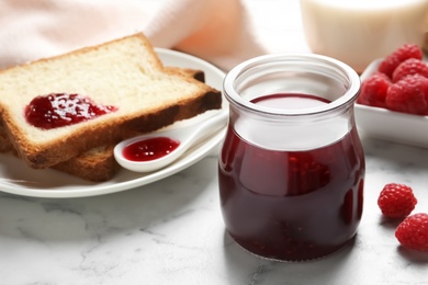 Image of Sweet raspberry jam and toasts for breakfast on white marble table