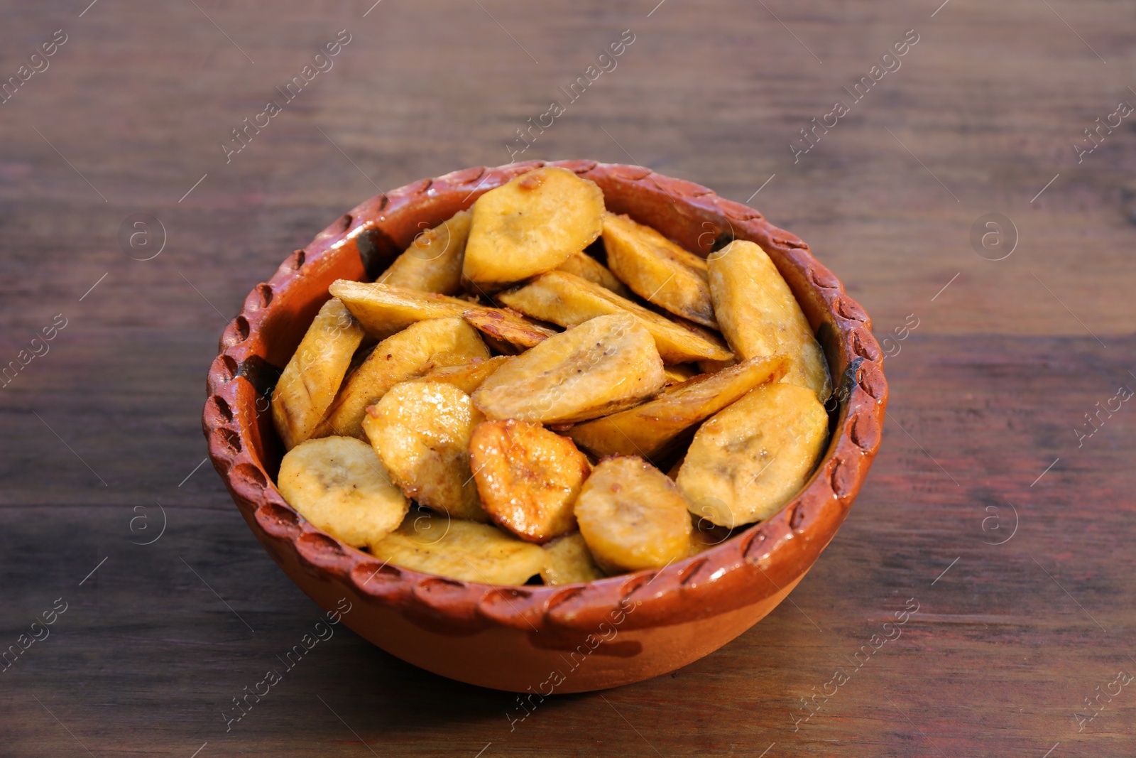 Photo of Tasty deep fried banana slices on wooden table