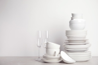 Photo of Set of clean tableware on white table