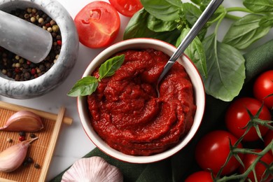 Photo of Tasty tomato paste in bowl and ingredients on table, flat lay