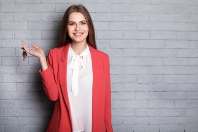 Photo of Beautiful real estate agent with key on brick wall background