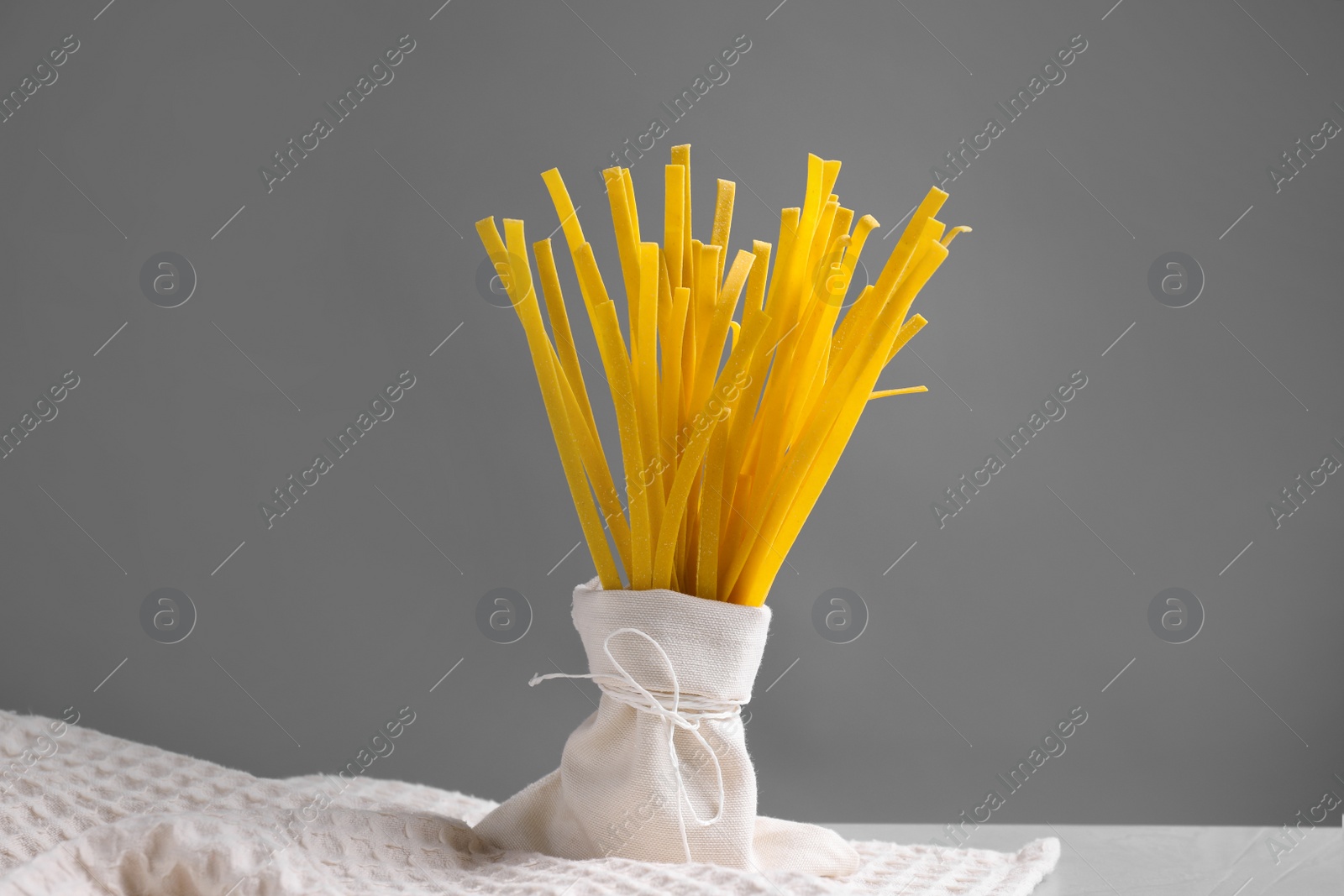 Photo of Uncooked noodles on table against grey background. Italian pasta