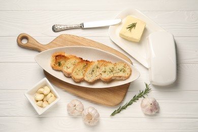 Tasty baguette with garlic and dill served on white wooden table, flat lay