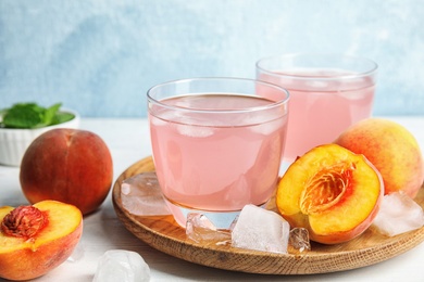 Photo of Tasty peach cocktail in glasses on table. Refreshing drink