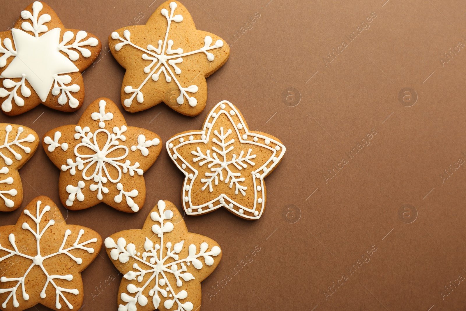 Photo of Tasty Christmas cookies with icing on brown background, flat lay. Space for text