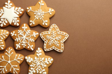 Photo of Tasty Christmas cookies with icing on brown background, flat lay. Space for text