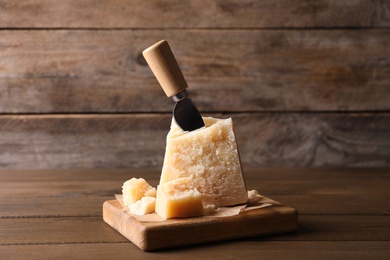 Delicious parmesan cheese with knife on wooden table