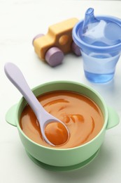 Photo of Bowl and spoon with tasty pureed baby food on white table