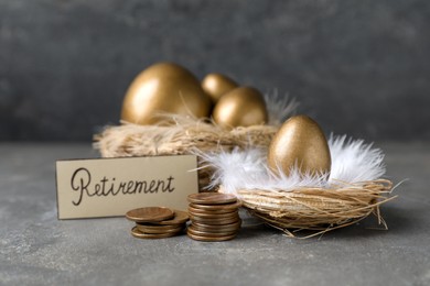 Photo of Many golden eggs, coins and card with word Retirement on grey table. Pension concept