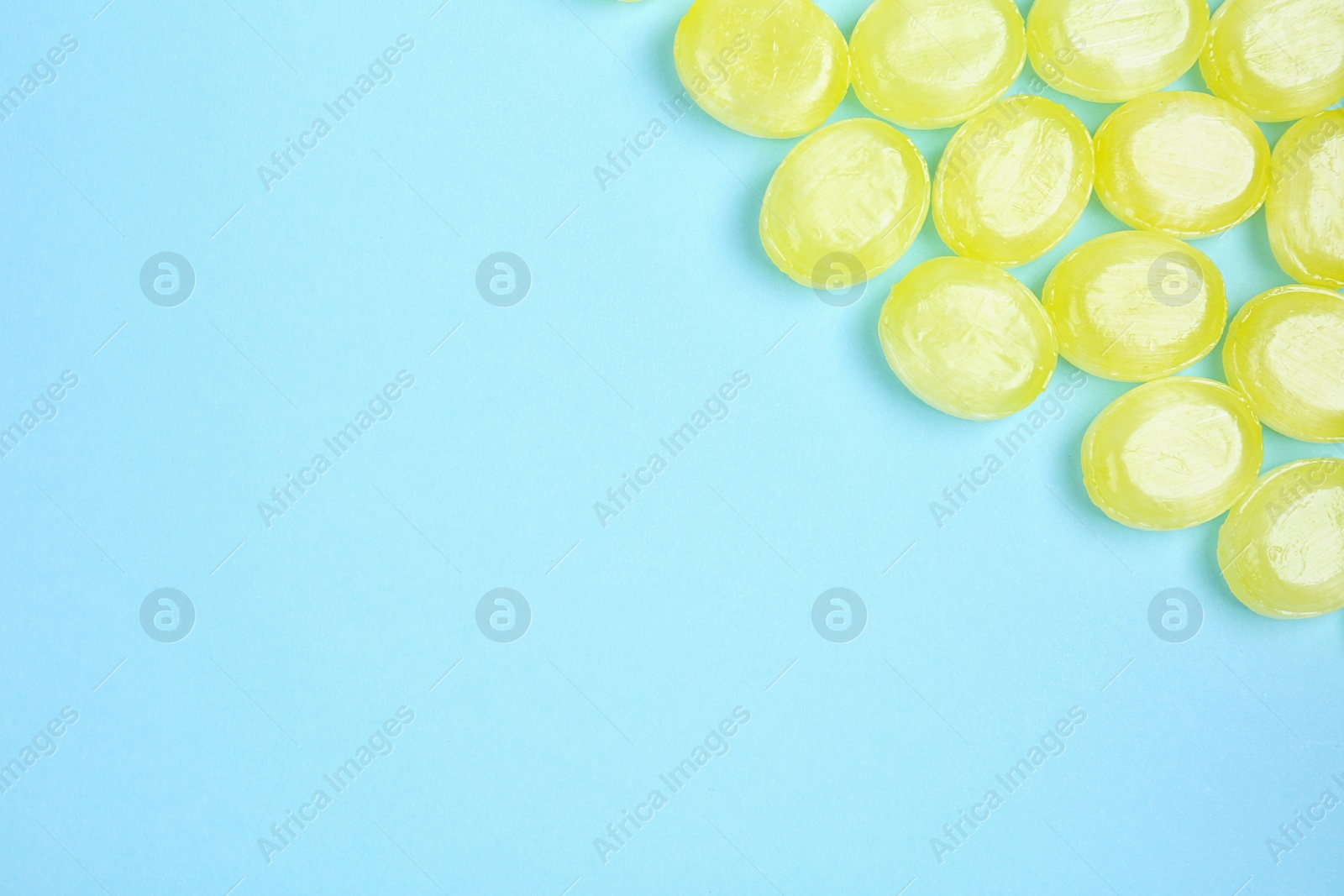 Photo of Many delicious lemon drops on light blue background, flat lay. Space for text