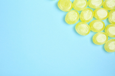 Photo of Many delicious lemon drops on light blue background, flat lay. Space for text