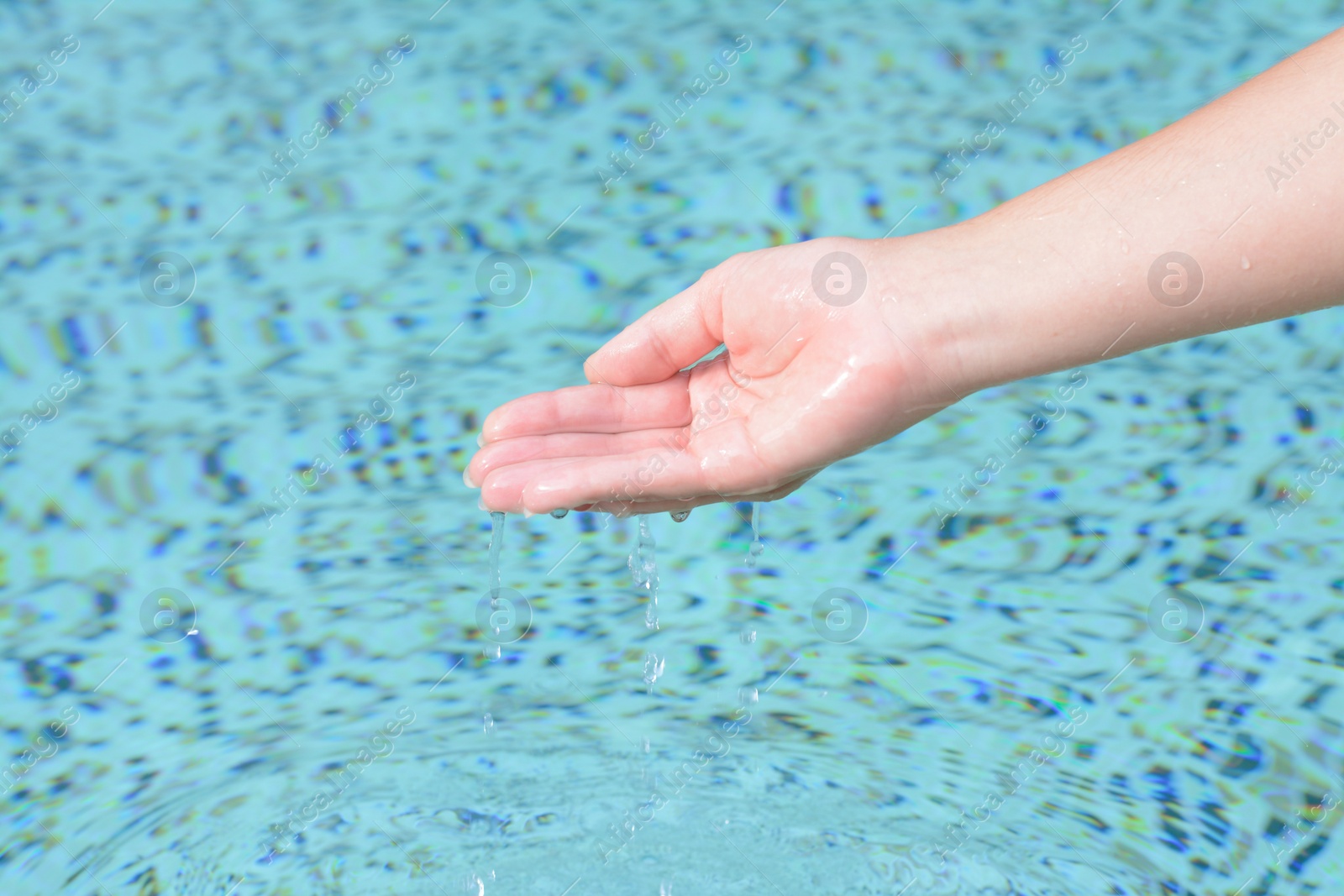 Photo of Girl pouring water from hand in pool, closeup