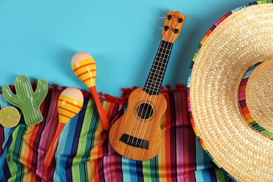 Flat lay composition with Mexican sombrero hat, maracas and ukulele on light blue table