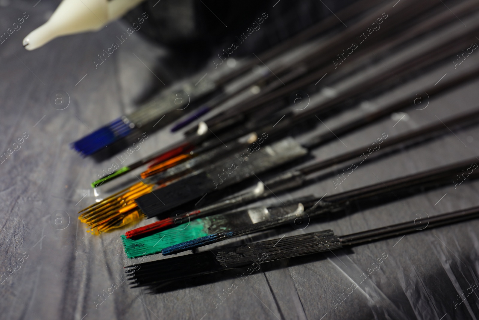 Photo of Tattoo needles covered with colorful inks on table, closeup