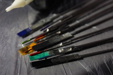 Photo of Tattoo needles covered with colorful inks on table, closeup