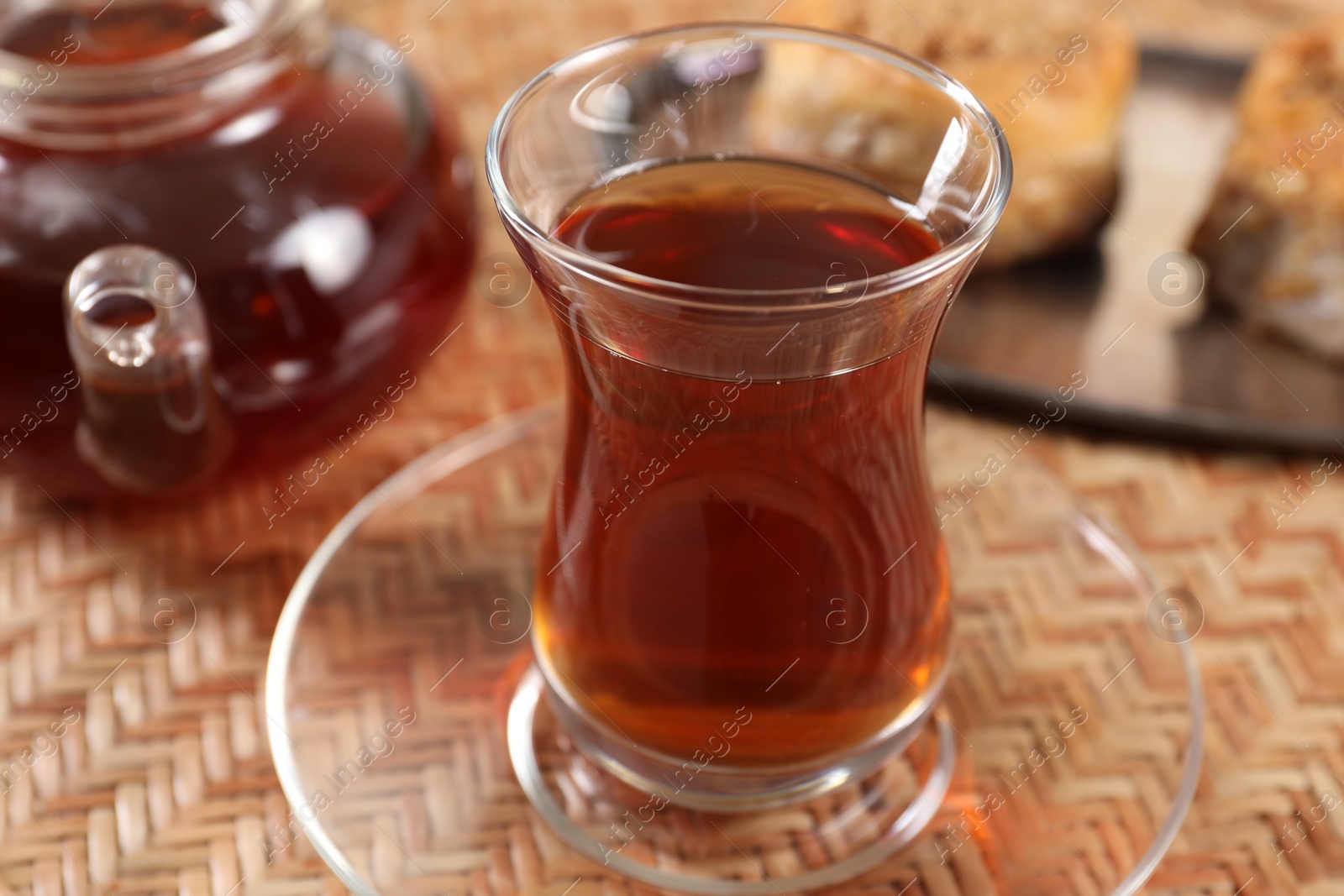 Photo of Traditional Turkish tea in glass on wicker table, closeup