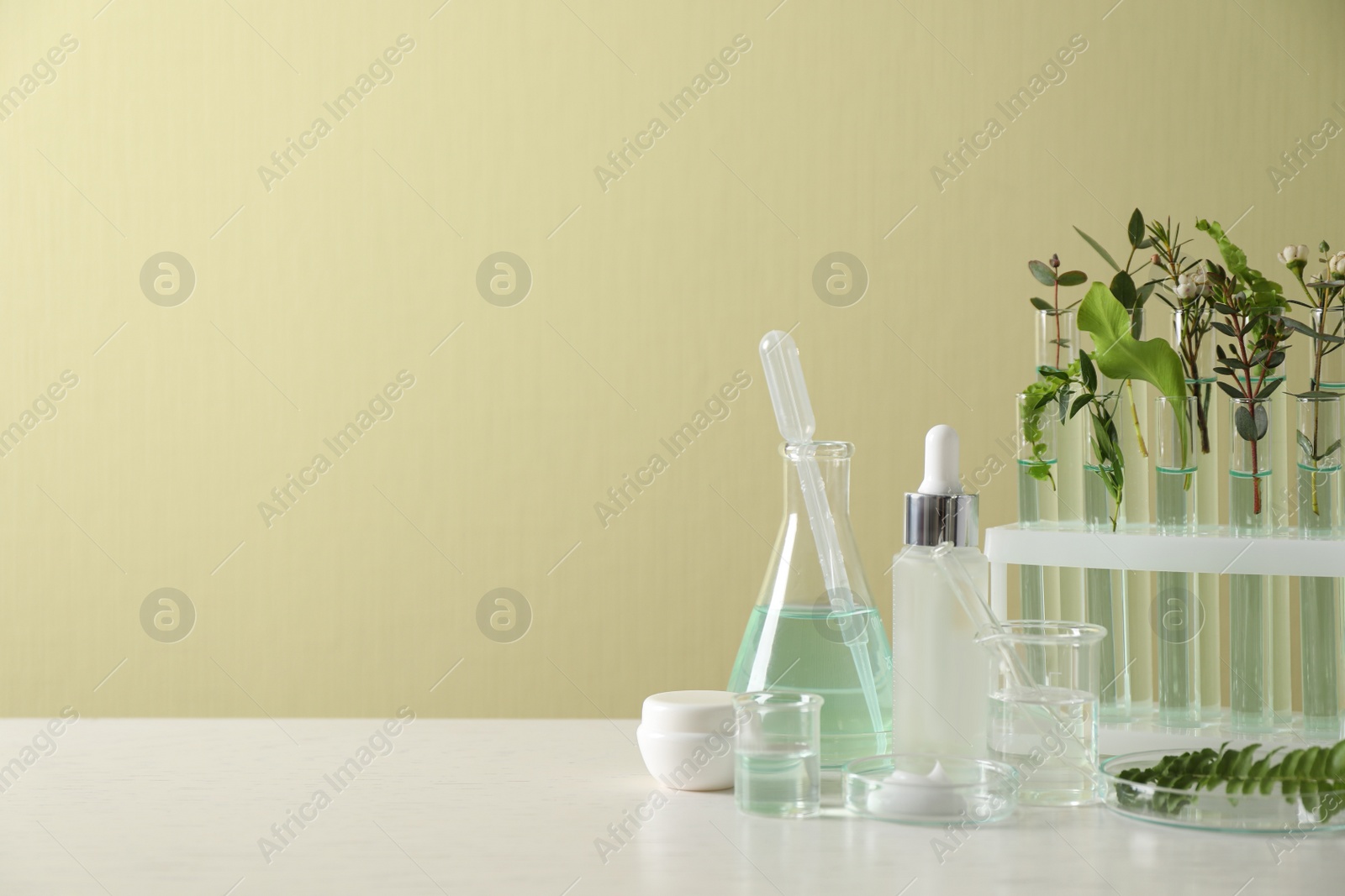 Photo of Natural ingredients for cosmetic products and laboratory glassware on white table