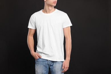 Photo of Man wearing white t-shirt on black background, closeup. Mockup for design