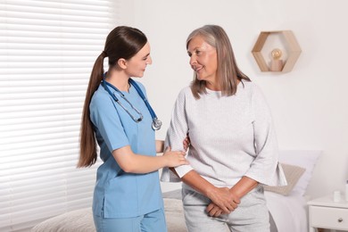 Photo of Young healthcare worker assisting senior woman indoors