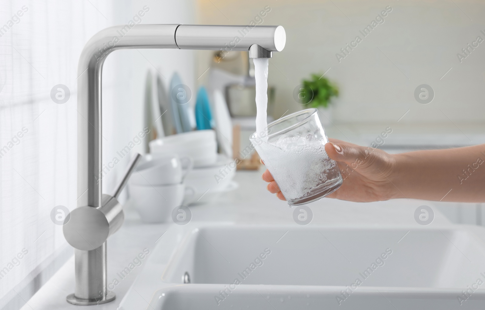 Photo of Woman filling glass with water from tap in kitchen, closeup