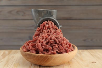 Mincing beef with manual meat grinder on wooden table