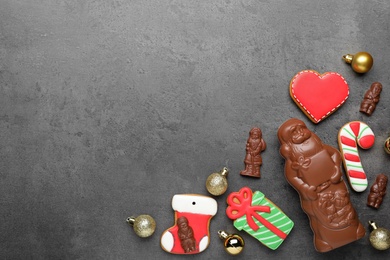 Photo of Flat lay composition with chocolate Santa Claus candies and Christmas cookies on grey table, space for text