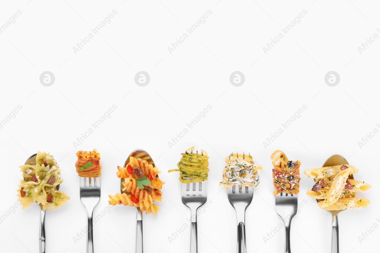 Photo of Forks and spoons with various tasty pasta on white background, flat lay. Space for text