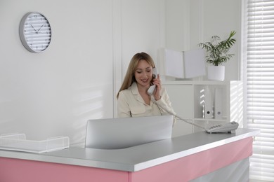 Photo of Receptionist talking on phone at countertop in office
