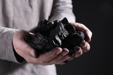 Man with handful of coal on dark background, closeup