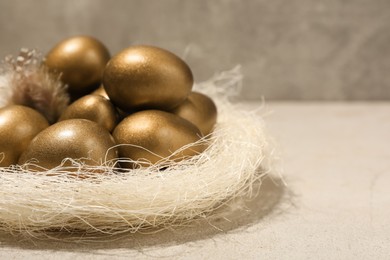 Golden eggs in nest on light table, space for text