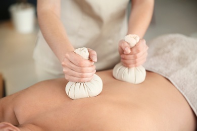 Man receiving herbal bag massage in spa salon, closeup