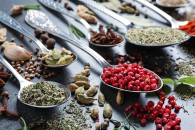 Photo of Different natural spices and herbs on black table, closeup