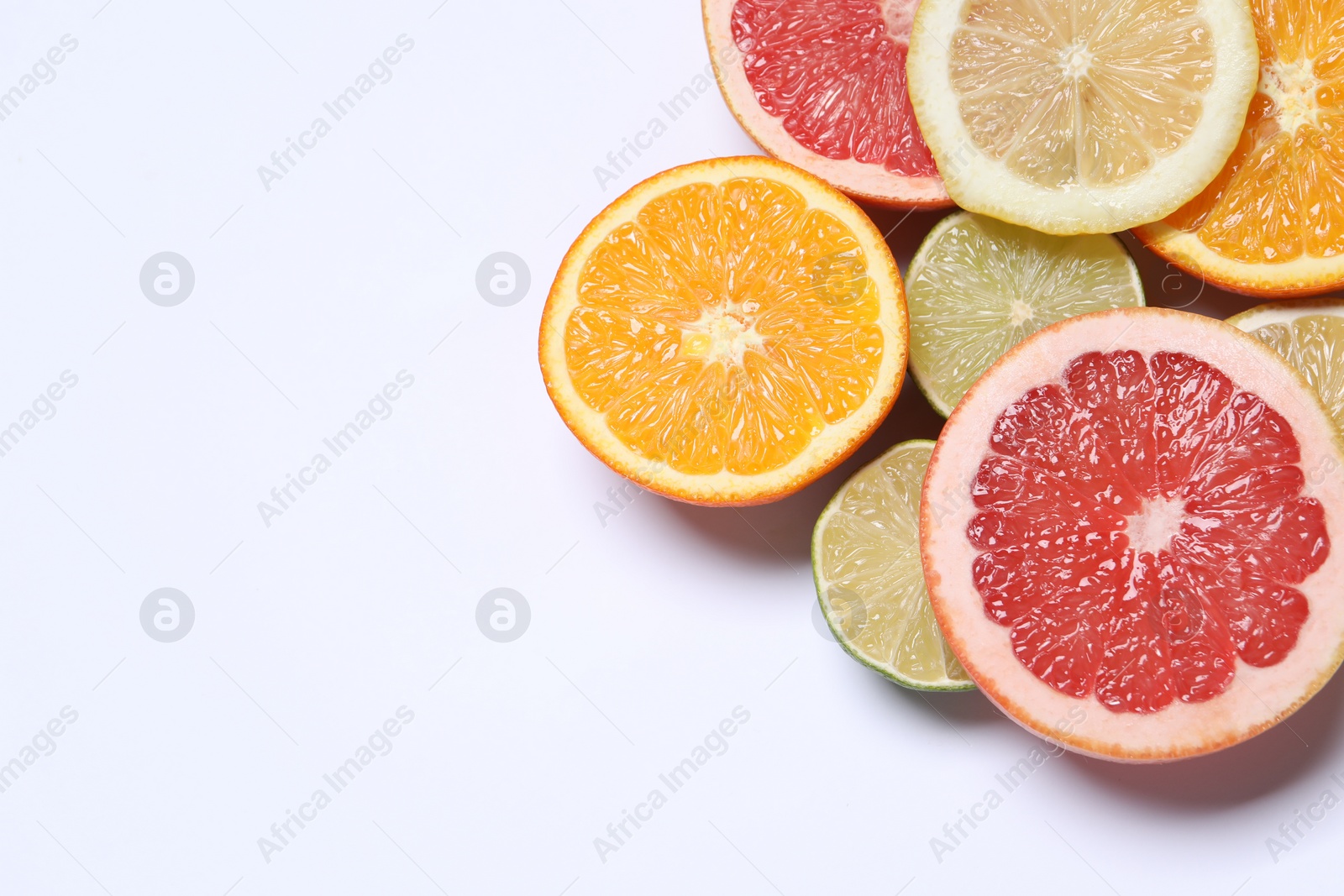 Photo of Different cut citrus fruits on white table, flat lay. Space for text