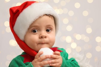 Photo of Cute baby in Christmas costume against blurred lights, closeup