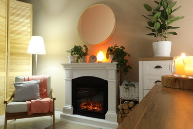 Photo of Stylish fireplace near comfortable armchair in cosy living room. Interior design