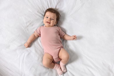 Photo of Sad little baby lying on bed, top view