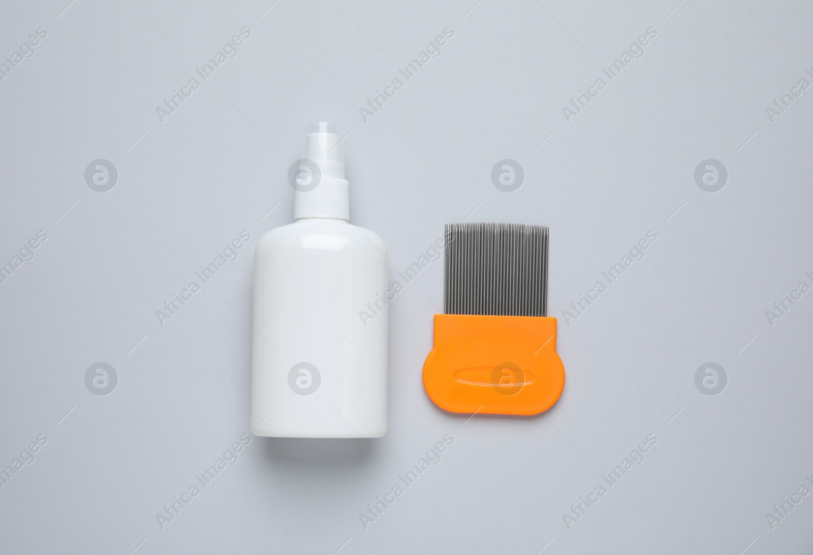 Photo of Spray and metal comb for anti lice treatment on light grey background, flat lay