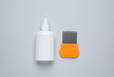 Spray and metal comb for anti lice treatment on light grey background, flat lay