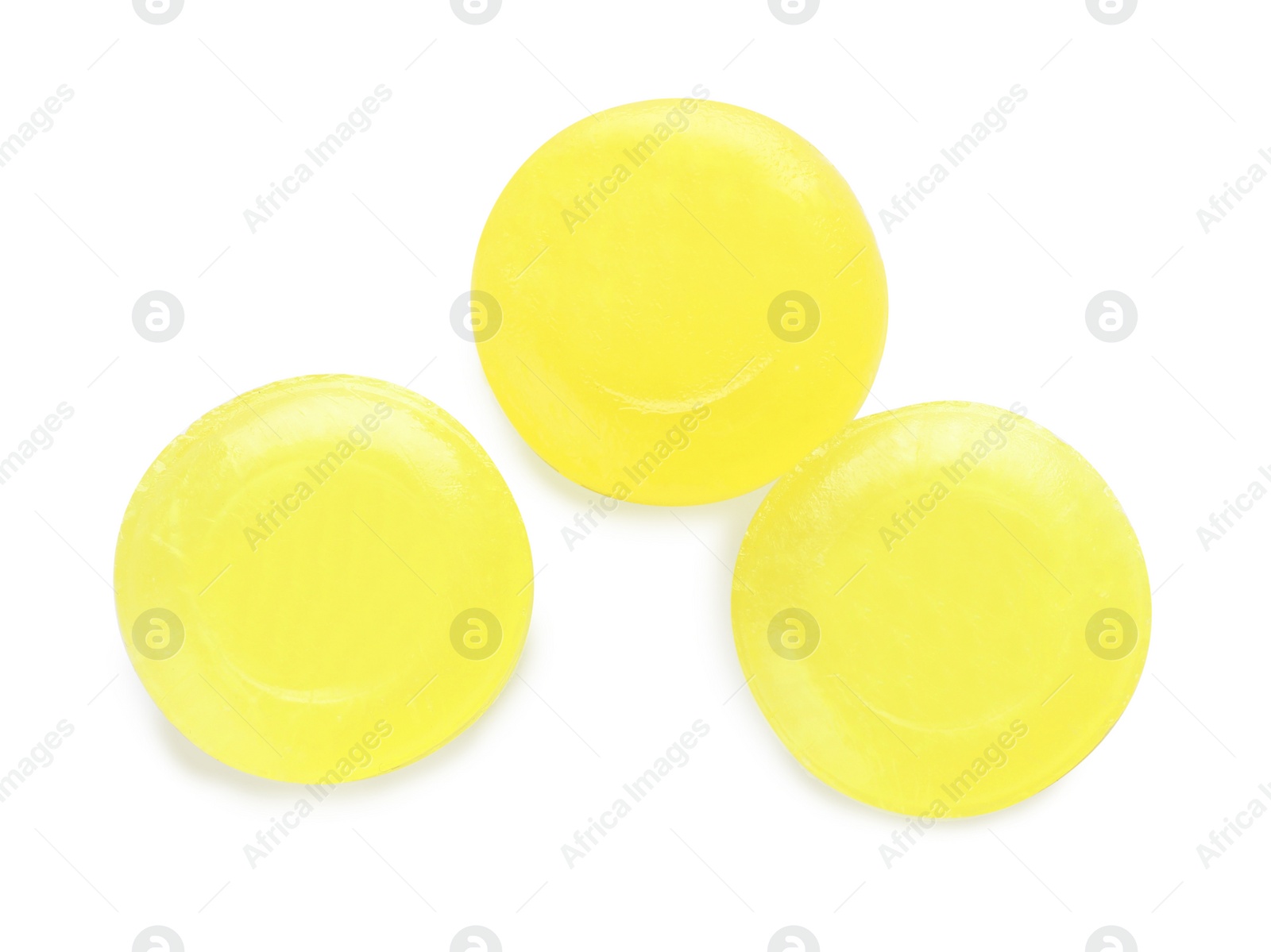 Photo of Three yellow cough drops on white background, top view