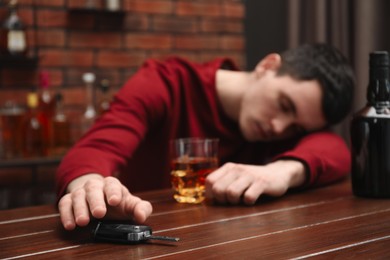 Photo of Drunk man reaching for car keys at table, closeup. Don't drink and drive concept