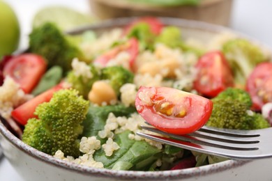 Photo of Healthy meal. Eating tasty salad with quinoa, chickpeas and vegetables, closeup