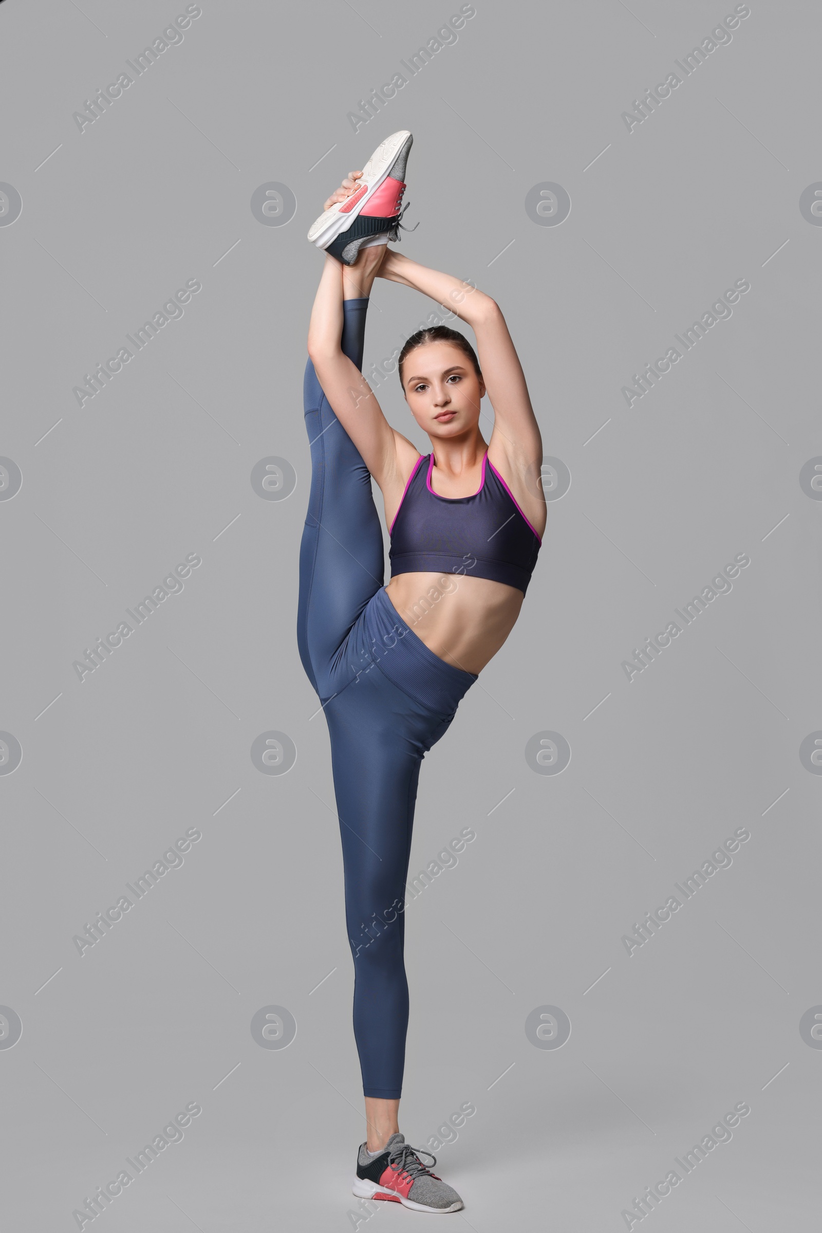 Photo of Woman stretching on grey background. Training exercise