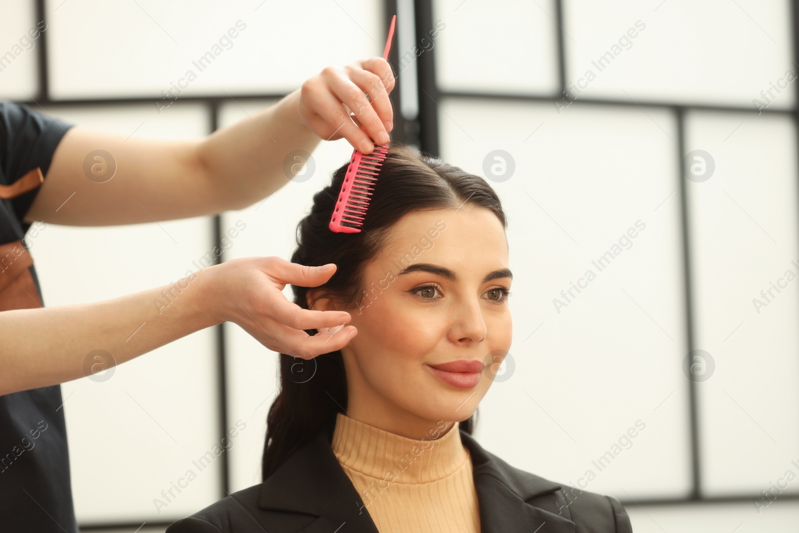 Photo of Hair styling. Professional hairdresser combing woman's hair indoors, closeup