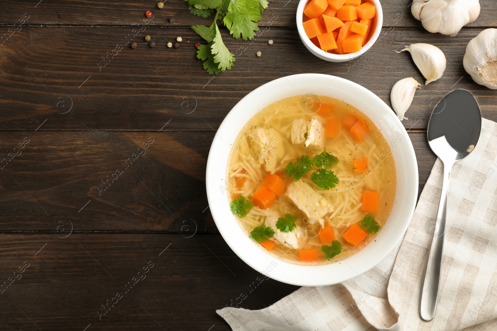 Photo of Homemade chicken soup served on wooden table, top view with space for text